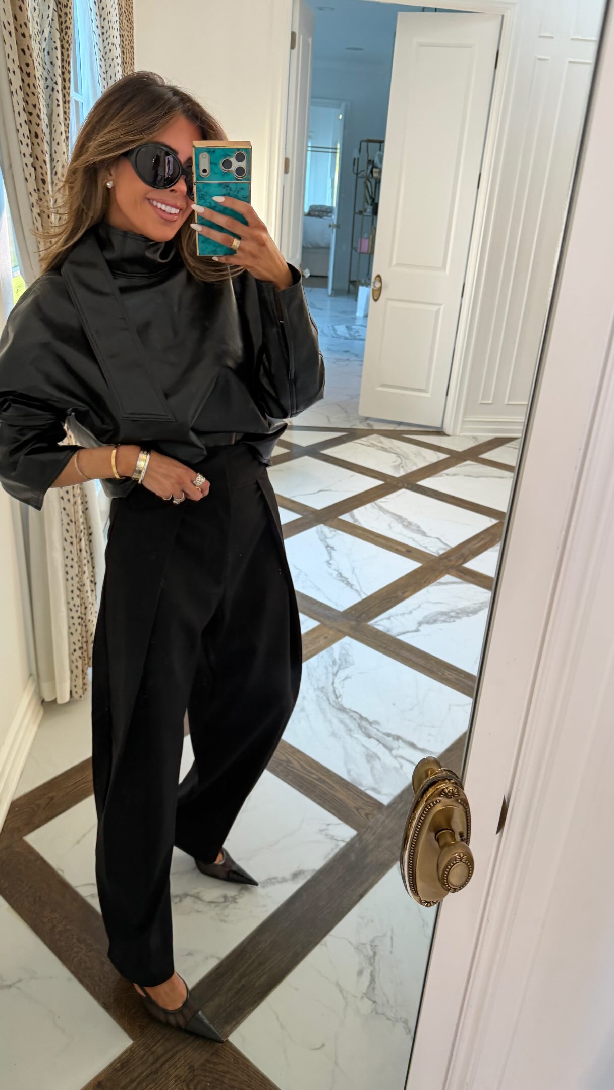 Woman in a black outfit posing indoors with black pointed shoes.