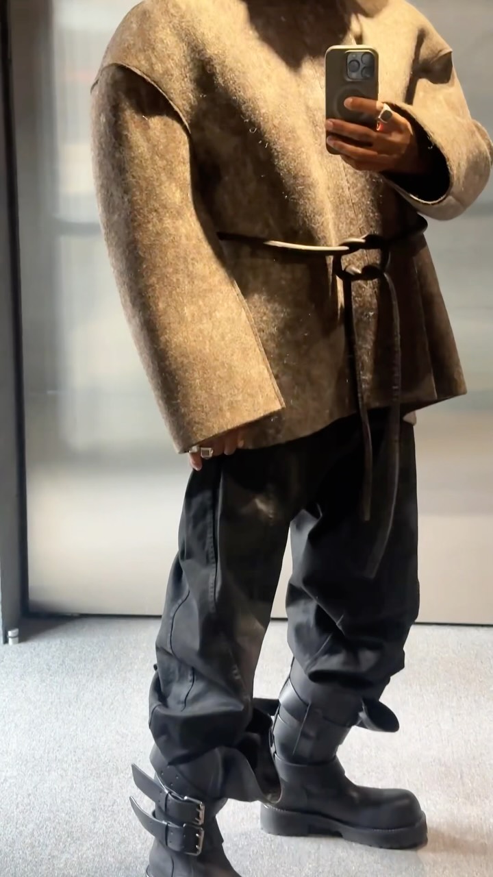 Close view of a brown jacket styled with black trousers and black boots.