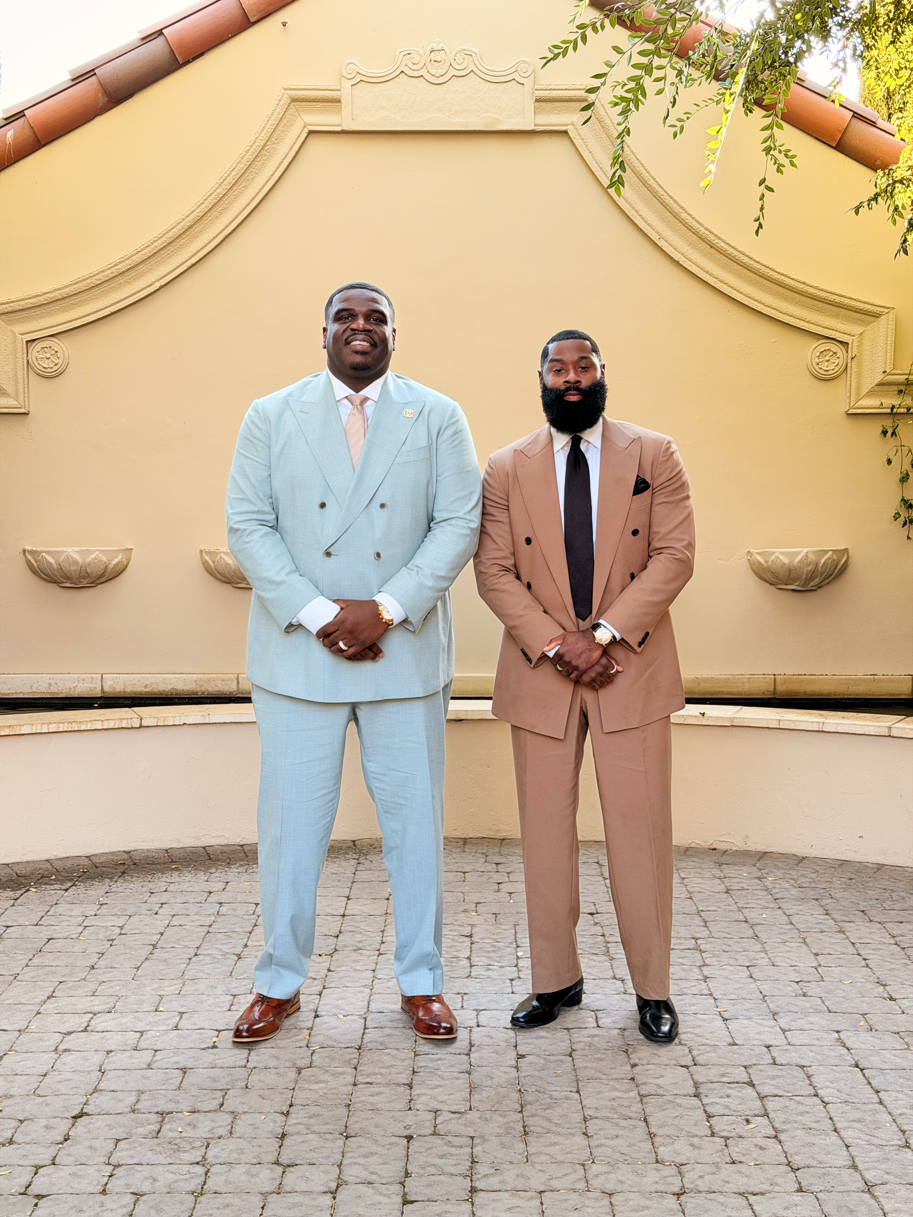 Two men in pastel suits wearing polished dark dress shoes.